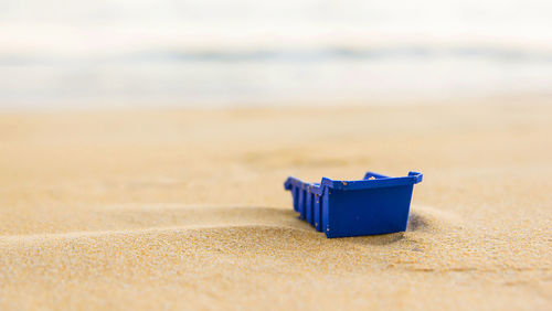 Close-up of plastic container on sand at beach