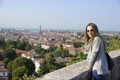 Portrait of young woman standing against cityscape