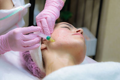 The doctor gives injections of blood plasma into the face of a young girl.