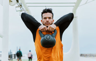 Man exercising with kettlebell at beach