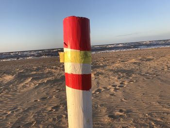 Red wooden posts on beach against clear sky