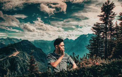 Young man standing on mountain against sky