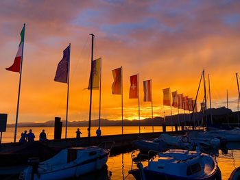 Sailboats moored at harbor against sky during sunset