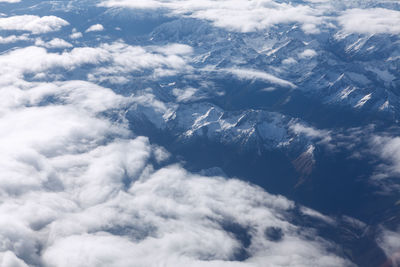 Clouds over the snowy mountains . mountains view from the airplane window . alps in the winter