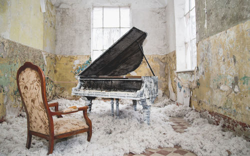 Old chair and piano in abandoned house