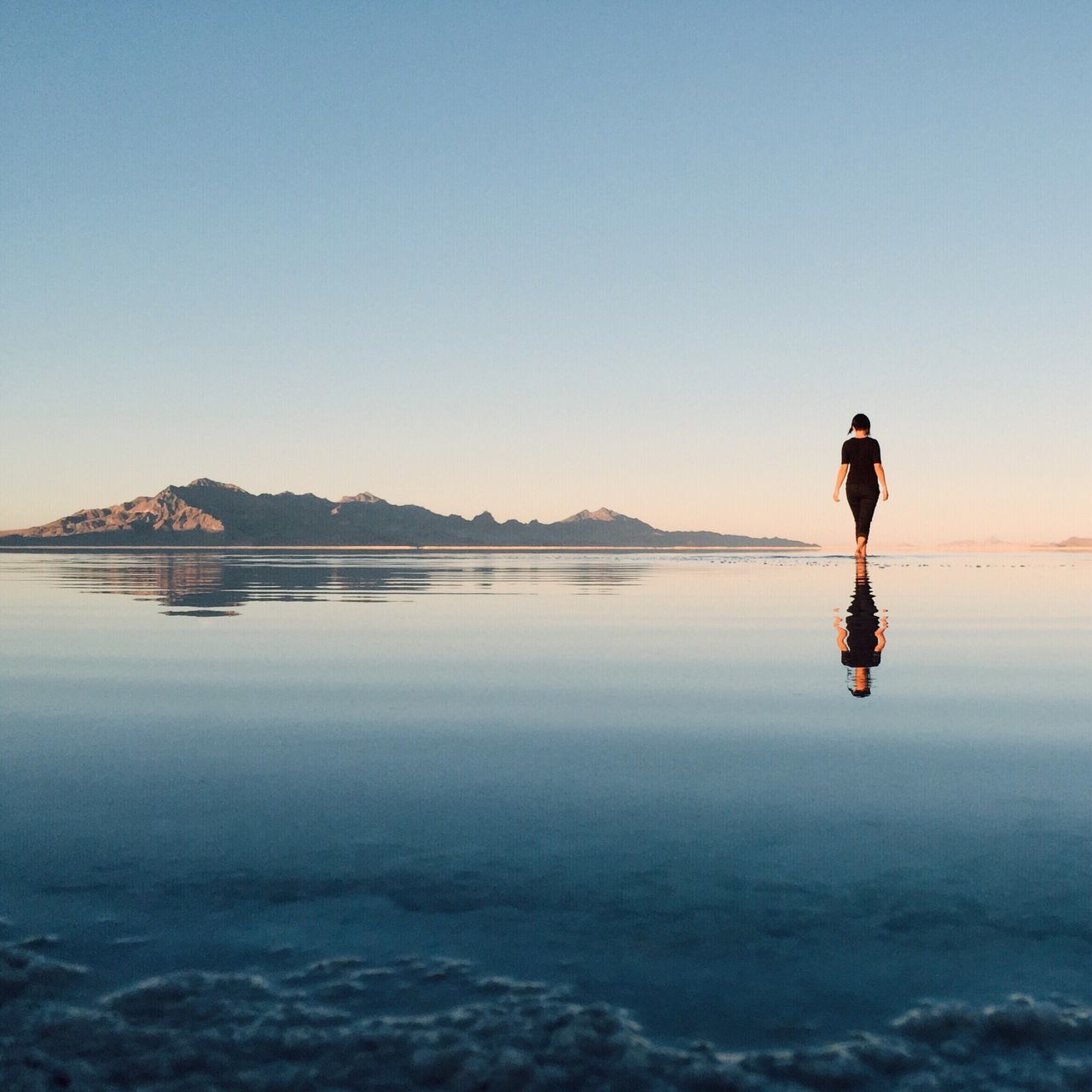 water, full length, leisure activity, lifestyles, copy space, clear sky, tranquil scene, tranquility, scenics, beauty in nature, standing, reflection, lake, rear view, men, nature, waterfront, silhouette