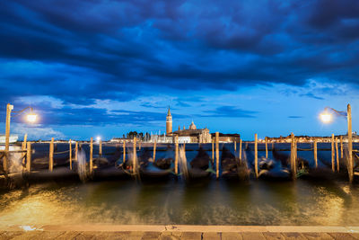 Blurred motion of boats moored on canal against sky