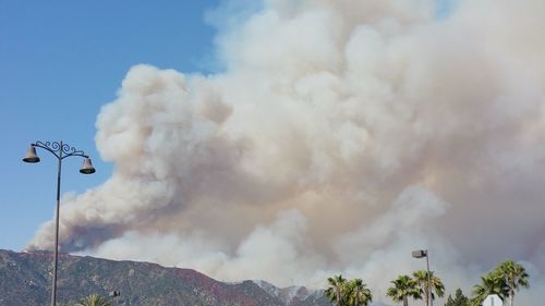 Scenic view of mountains against smoke in sky