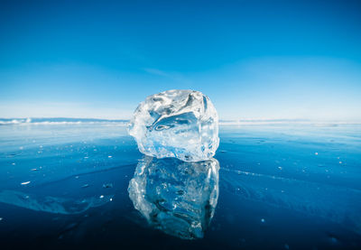 Close-up of ice crystals on sea against blue sky