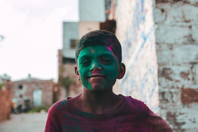 Portrait of smiling boy with green powder paint on face in town during holi