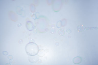 Close-up of bubbles flying against white background