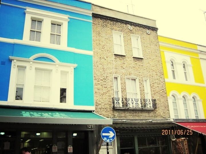 building exterior, architecture, built structure, window, blue, low angle view, building, residential building, balcony, city, residential structure, day, yellow, outdoors, multi colored, text, glass - material, sky, no people, facade