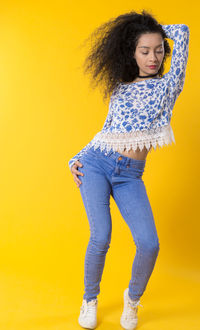 Portrait of woman standing against yellow background