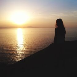 Silhouette woman looking at sea against sky during sunset