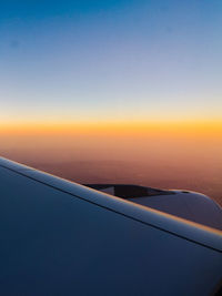 Airplane wing against sky during sunset