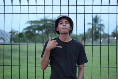 Portrait of man standing against fence