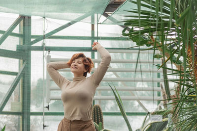 A beautiful plus size girl enjoying standing among the green plants