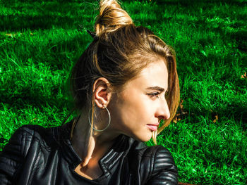 Young woman looking away on grassy field at park