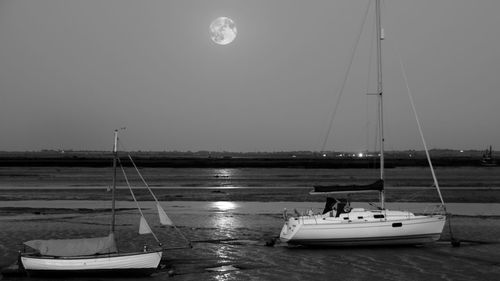 Boats sailing in sea against clear sky at night