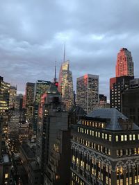 Modern buildings in city against cloudy sky