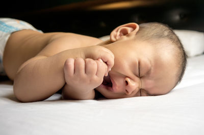 Close-up of baby lying on bed