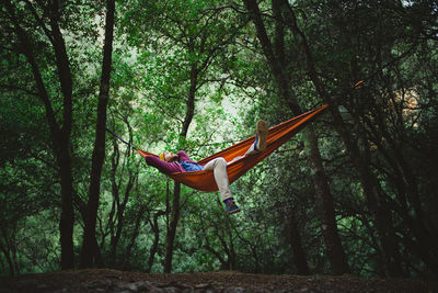 Girl hanging on tree trunk in forest