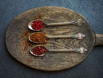 Close-up of chili flakes and dried fruits in spoons on wooden cutting board