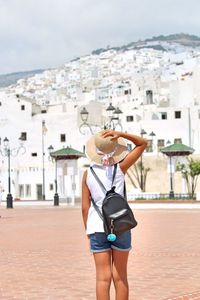 Rear view of woman standing against buildings in city