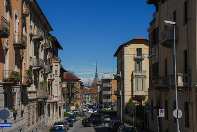 Cars on road by buildings against sky in city