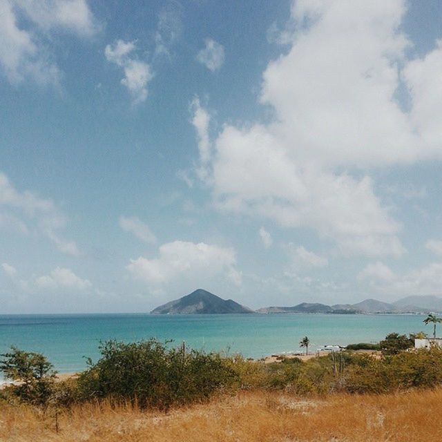 water, sky, sea, tranquil scene, tranquility, scenics, beauty in nature, cloud - sky, nature, beach, cloud, blue, grass, mountain, horizon over water, shore, idyllic, coastline, cloudy, day