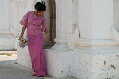 Woman standing by pink building