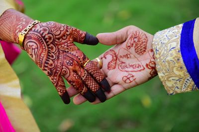 Cropped hands of bride and groom with henna tattoo