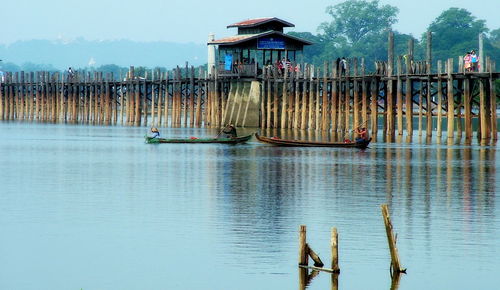 Wooden posts in lake against sky