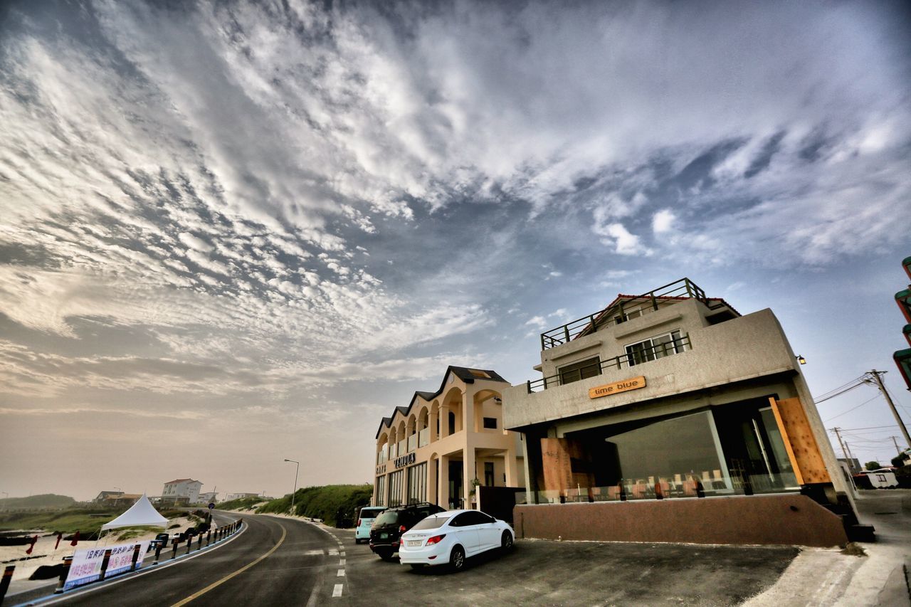 transportation, car, building exterior, sky, land vehicle, architecture, built structure, road, mode of transport, street, cloud - sky, cloud, the way forward, house, cloudy, city, outdoors, incidental people, residential building, day