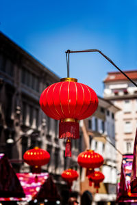 Low angle view of illuminated lanterns hanging by building against sky