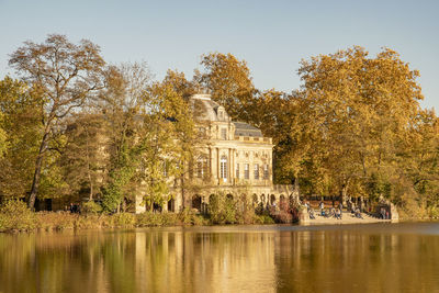 Trees by lake against building