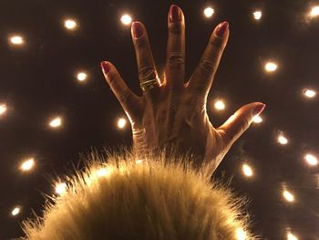 Close-up of woman hand against illuminated background