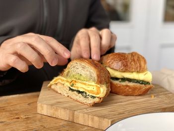 Close-up of hand holding bread on cutting board