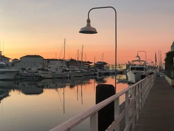 Boats moored in sea against sky during sunset