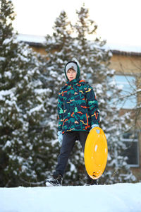 Winter portrait of a boy with a plastic sled sliding on a snowy slope