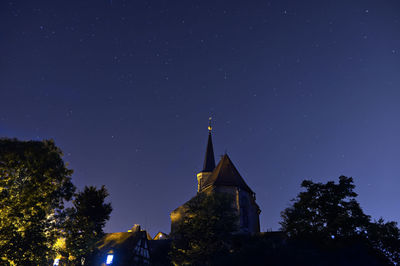 Low angle view of trees and building against sky at night