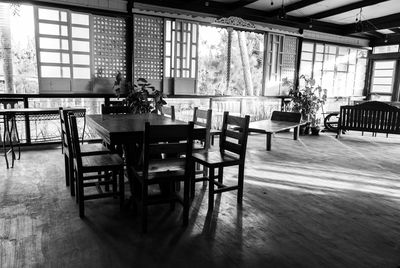 Empty chairs and table against window