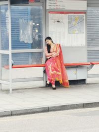 Full length of woman standing against red wall