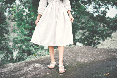 Low section of woman standing against trees