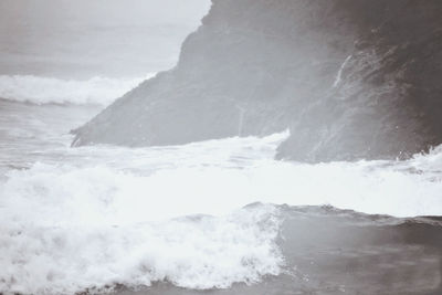 Waves splashing on shore against sky