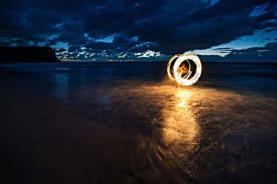 Person with illuminated wire wool on shore