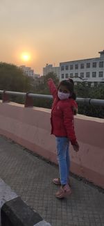 Full length portrait of woman standing against sky during sunset
