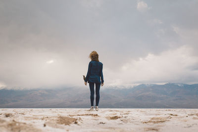 Rear view of woman standing on mountain against sky