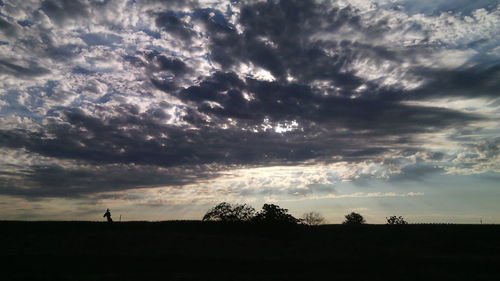 Silhouette of field against cloudy sky