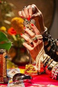 Cropped hands of woman holding champagne flute with jewelry